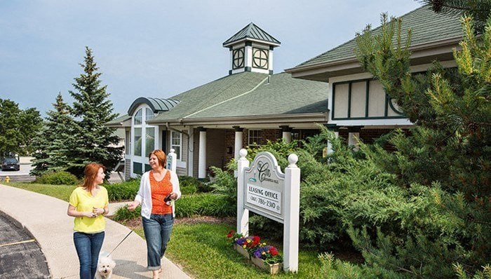 two women walking a dog in front of a building
