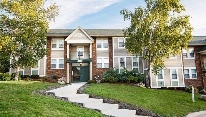 an apartment building with a lawn and trees in front of it