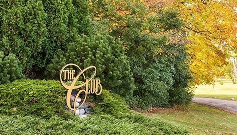 a sign in a grassy area with trees in the background
