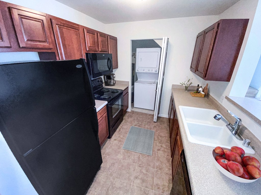a kitchen with a black refrigerator freezer next to a sink