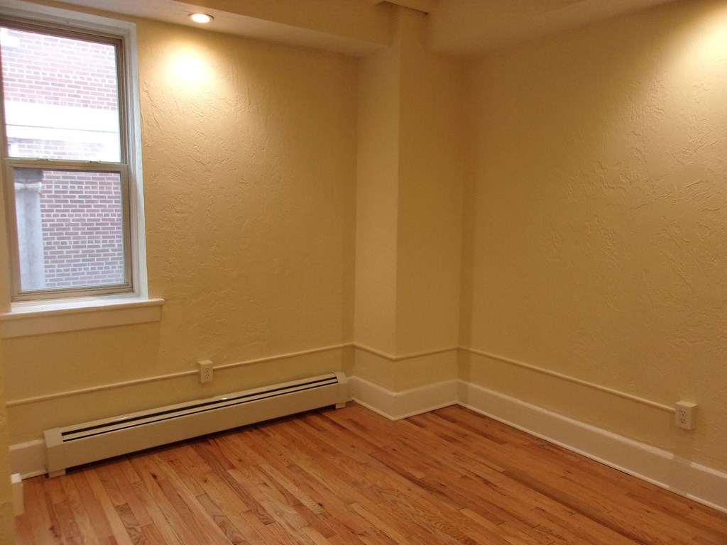 a corner of a room with a window and a wooden floor