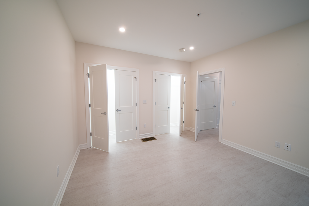 an empty living room with white doors and a white tile floor