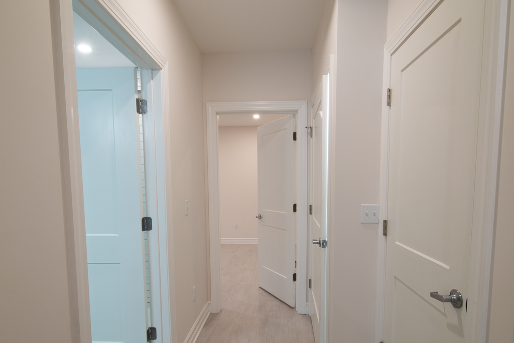 a hallway with a white door and a closet and a door to a bedroom