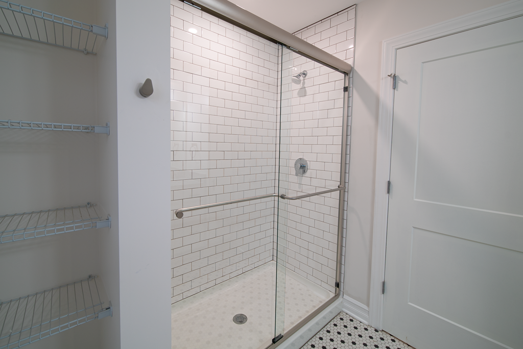 a white tiled shower in a bathroom with a white door