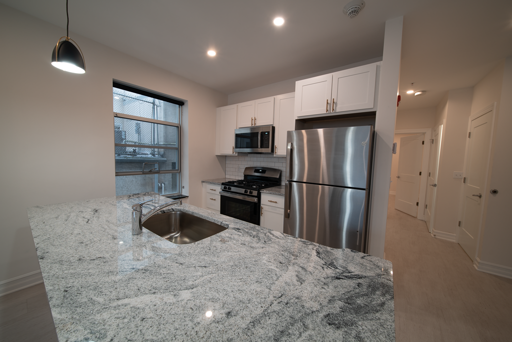 a kitchen with granite counter tops and a stainless steel refrigerator