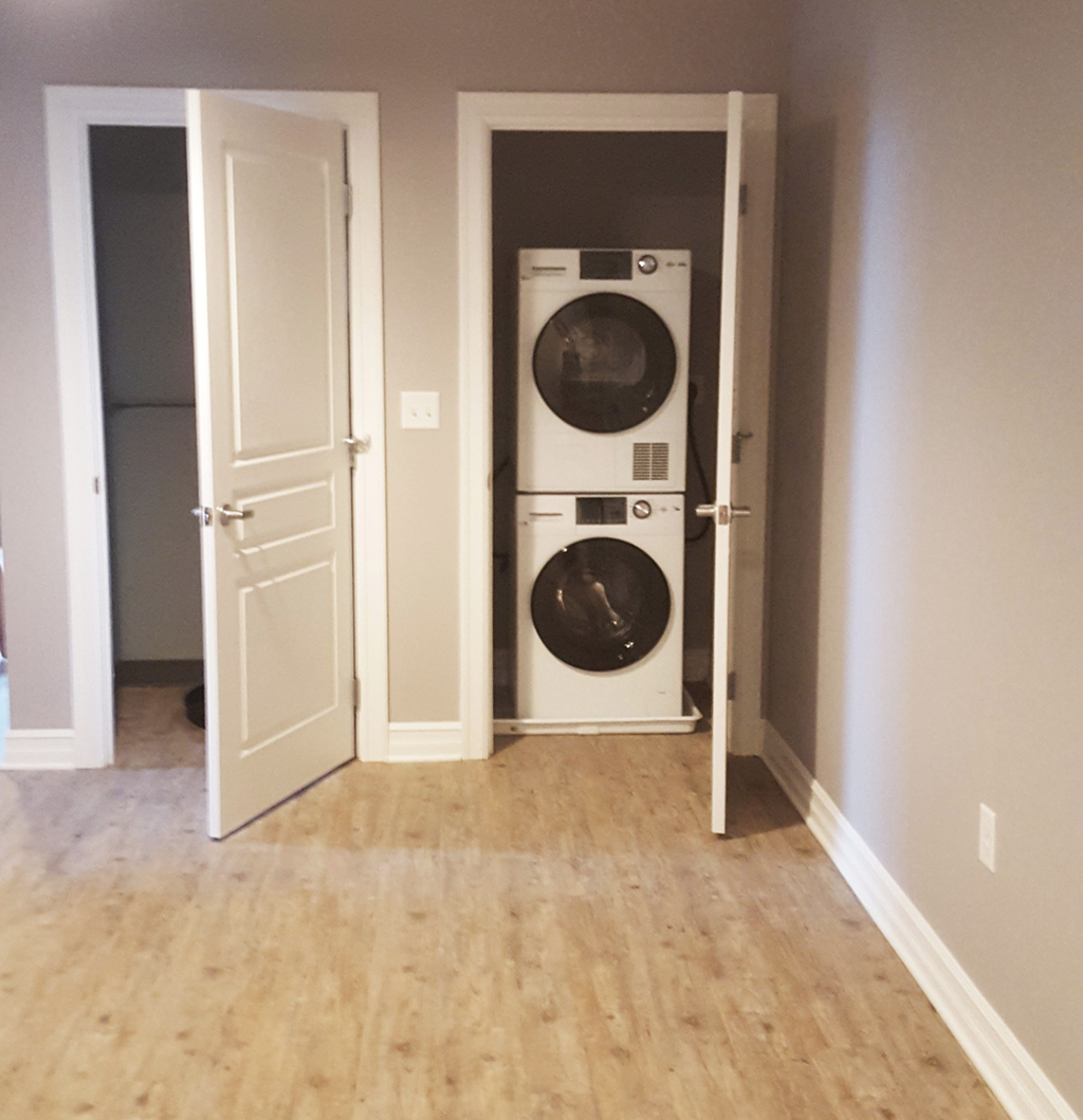 a front load washer and dryer in a hallway with a door to a