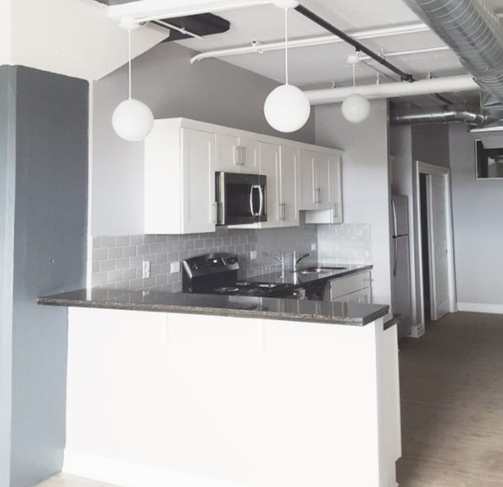a kitchen with white cabinets and a black counter top