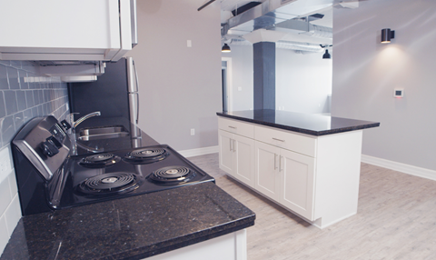 a kitchen with white cabinets and black counter tops and a stove top oven