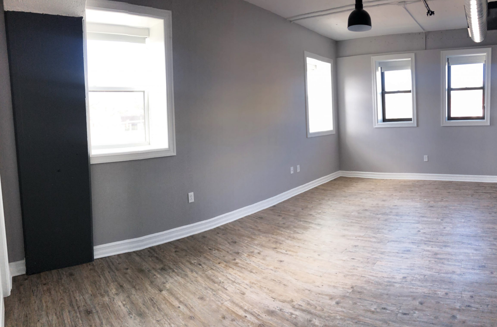 an empty living room with wood floors and gray walls