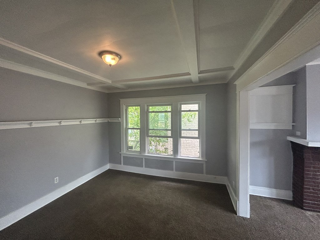 an empty living room with a brick fireplace and a window