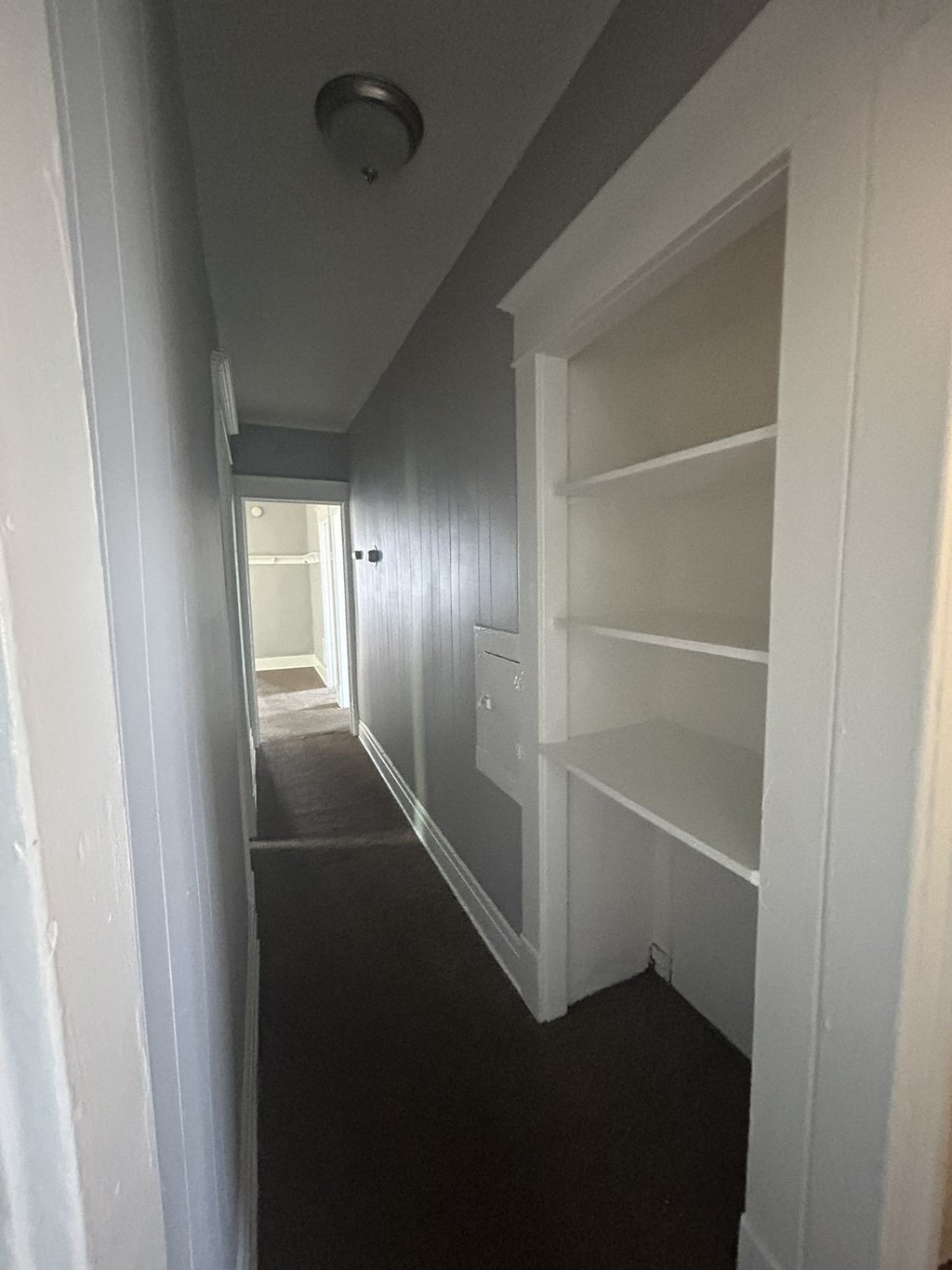 a hallway with white shelves and a door and a window