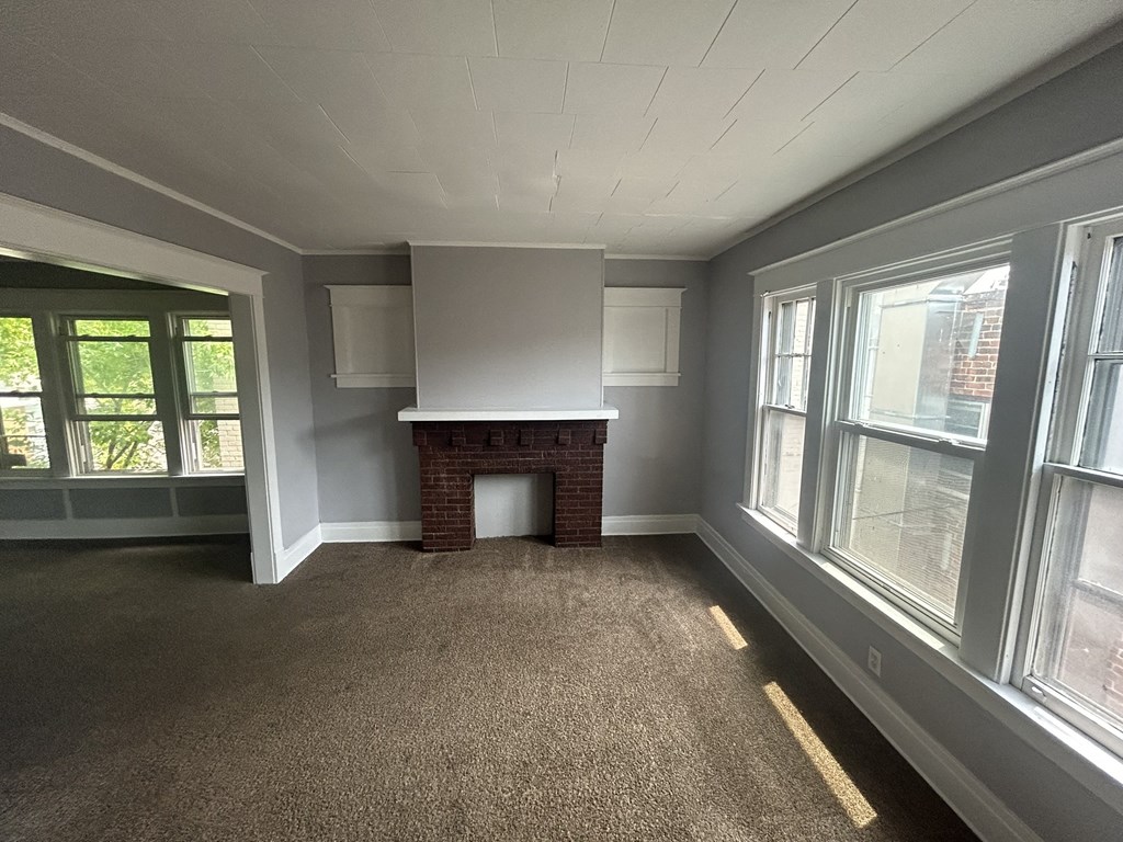 an empty living room with a fireplace and windows