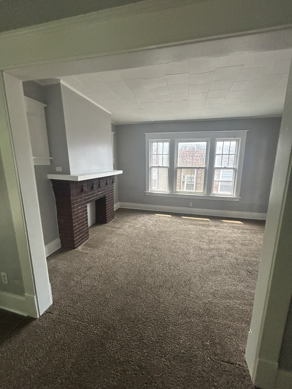 an empty living room with a fireplace and a window