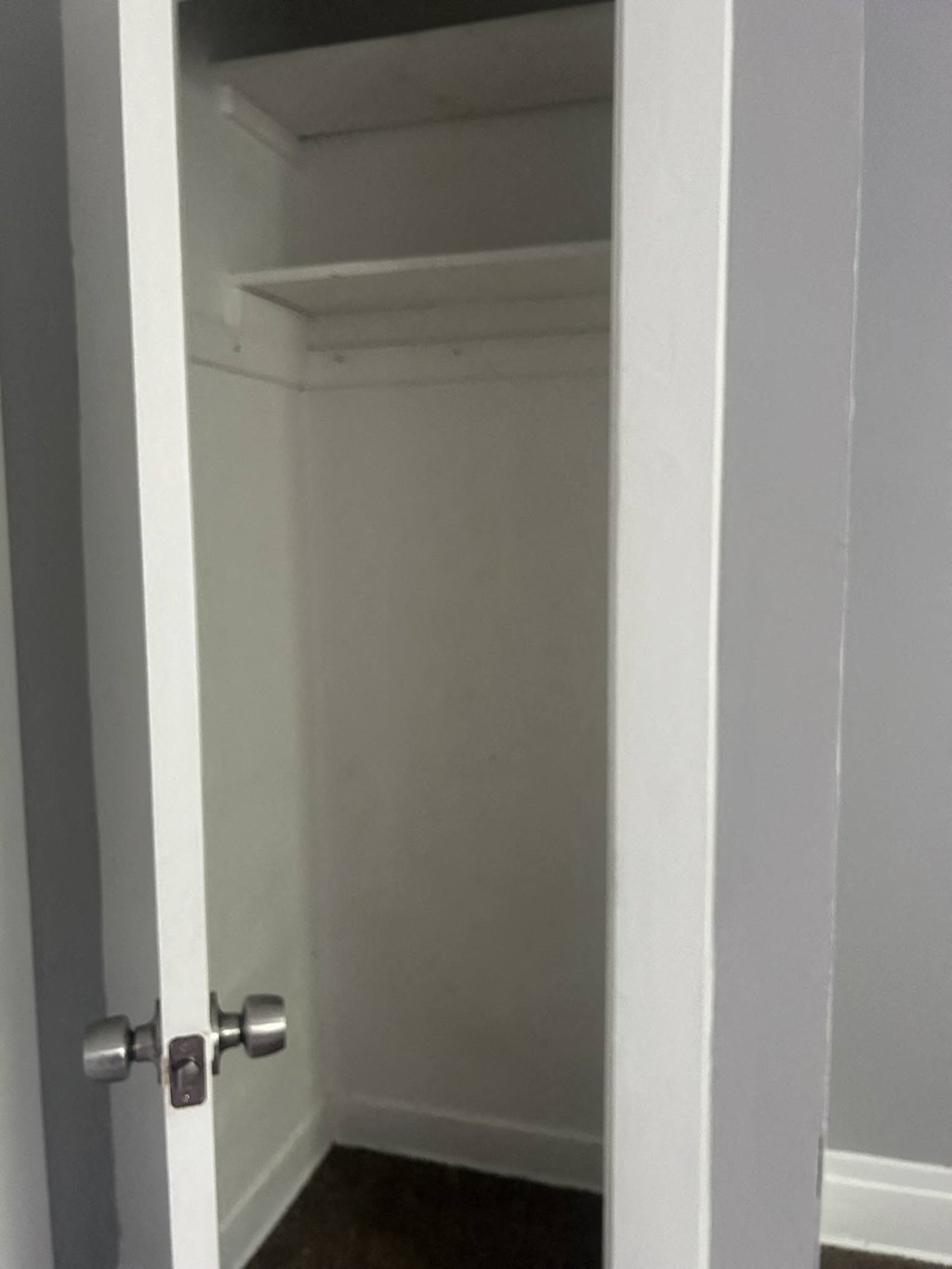 a small closet with a door open to a white room