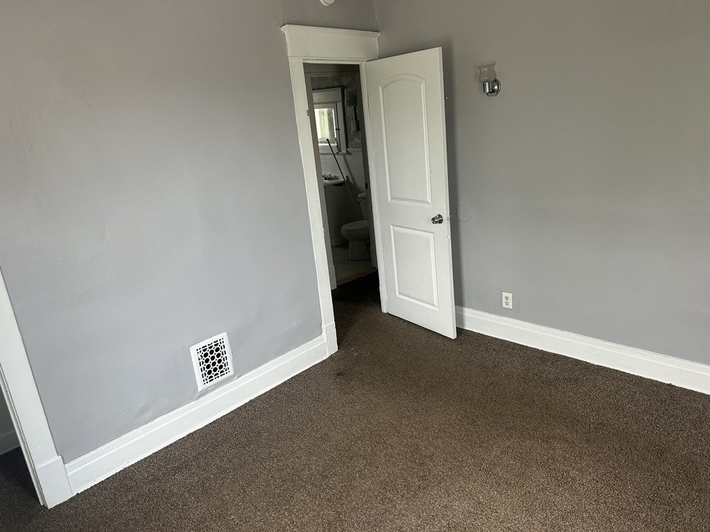 an empty room with a door to a bathroom and a closet