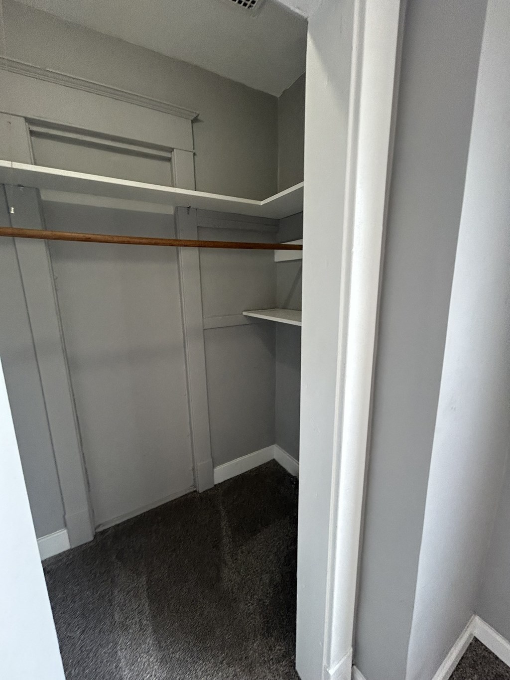 a walk in closet with white shelving and a carpet