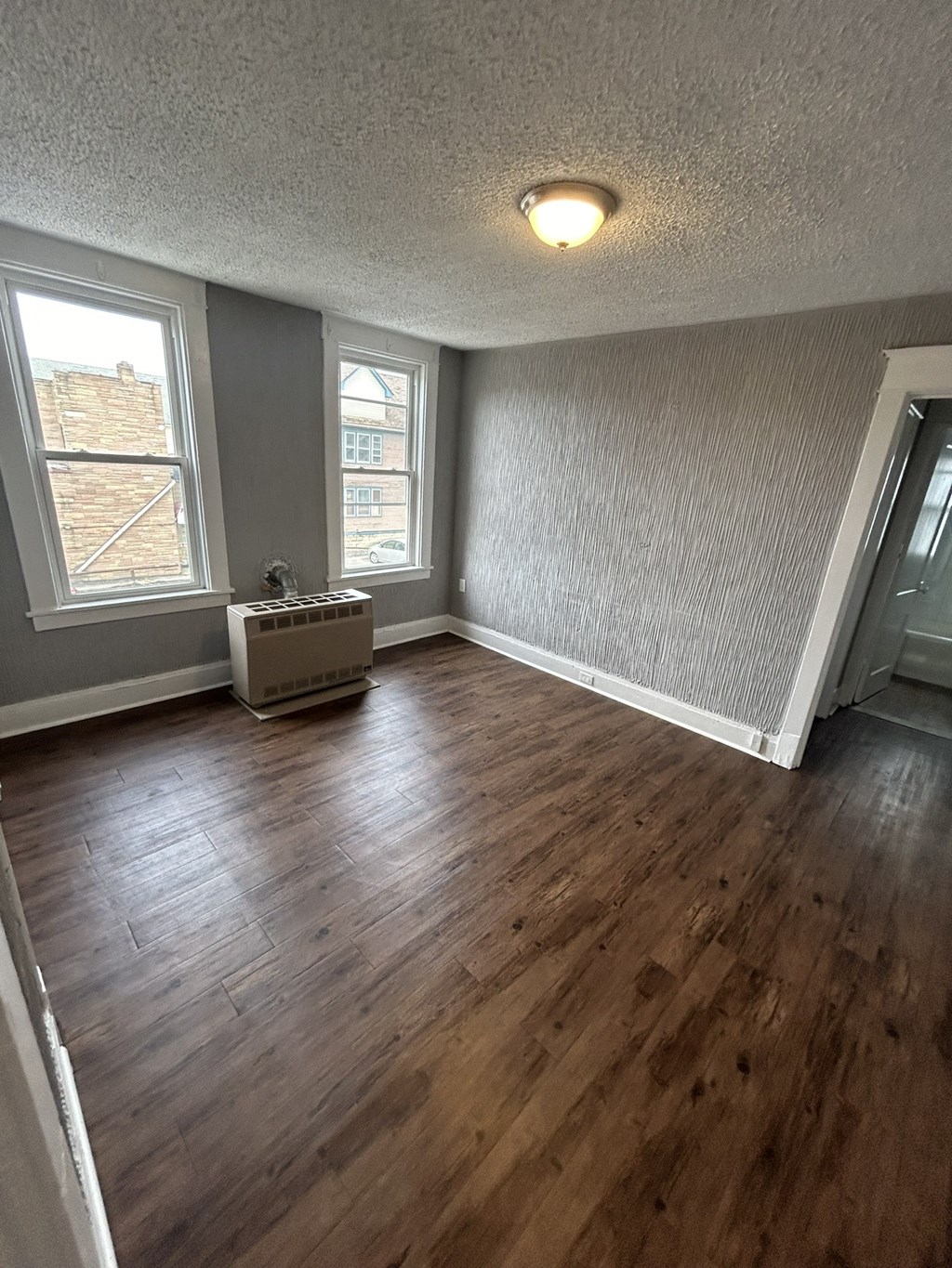 an empty living room with hardwood floors and a window
