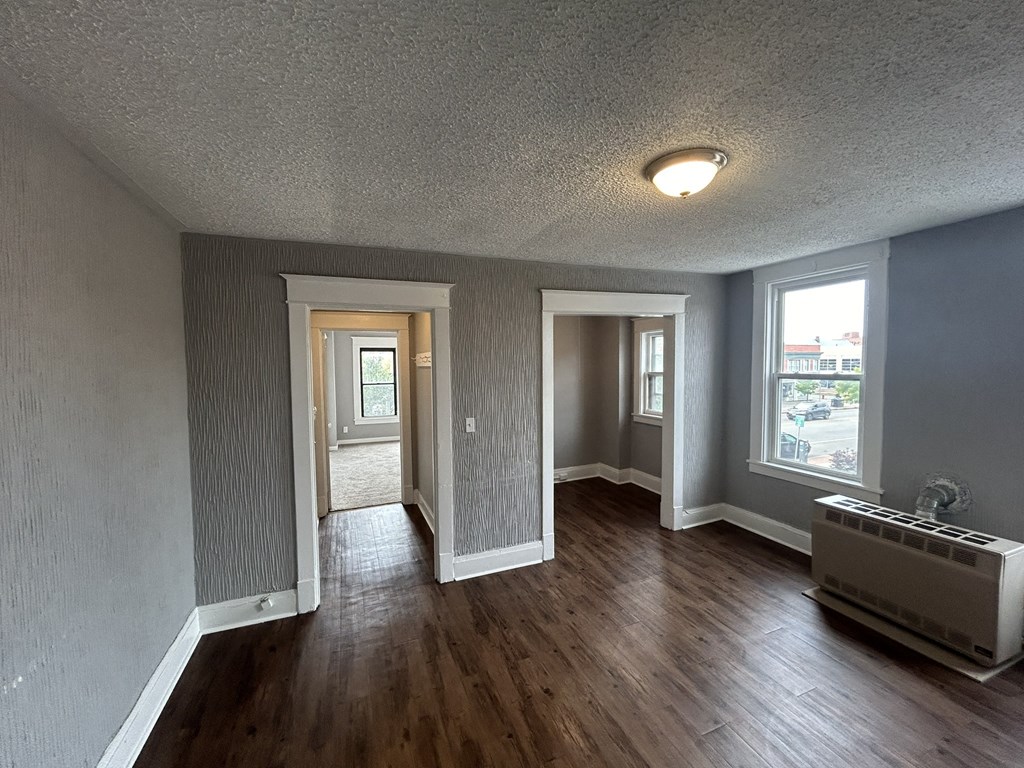 an empty living room with wood flooring and grey walls