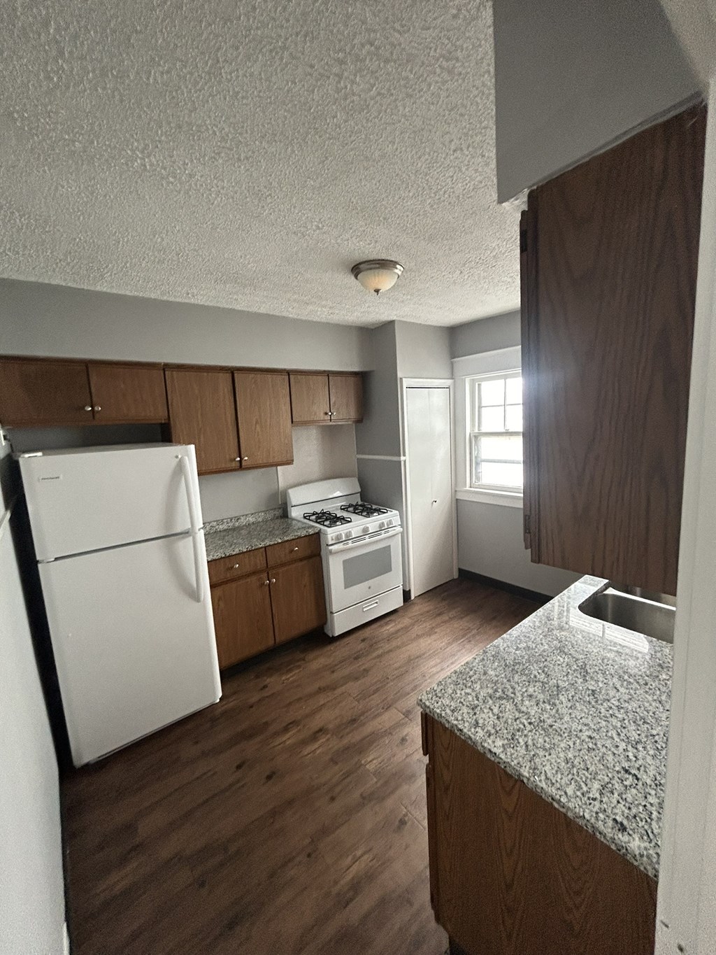an empty kitchen with white appliances and wooden cabinets