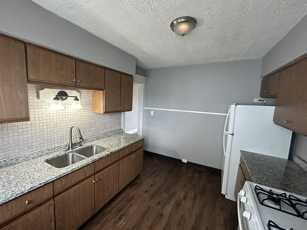 an empty kitchen with wood flooring and white appliances