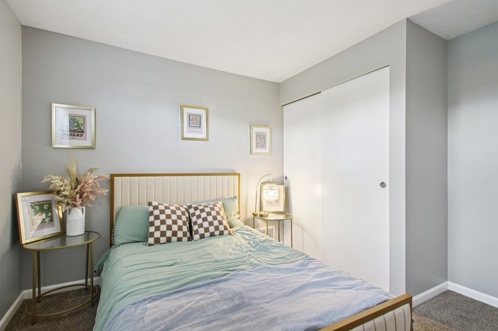 A bedroom with a bed, two lamps, and two pictures on the wall.