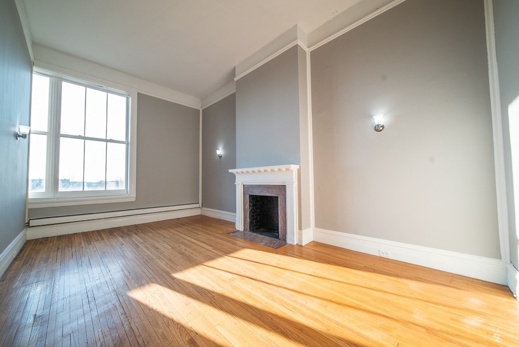 an empty living room with wood floors and a fireplace