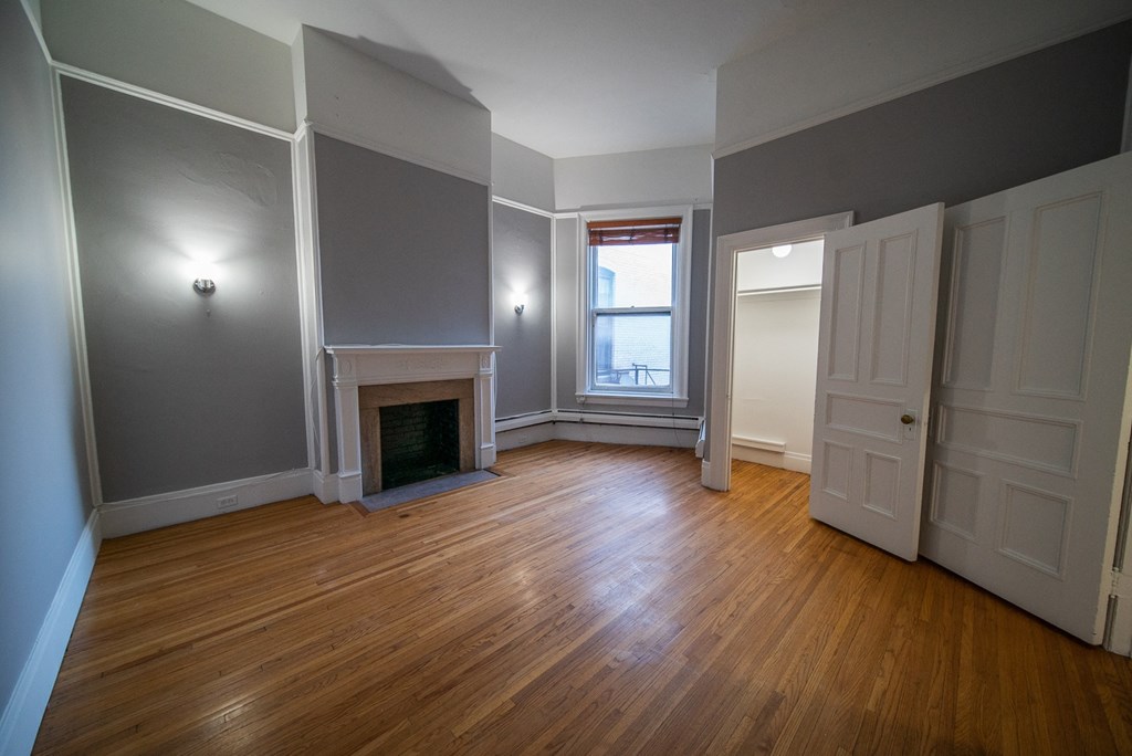 a living room with gray walls and a fireplace and wooden floors