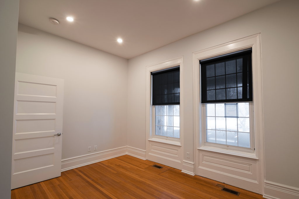 a living room with white walls and a door and two windows