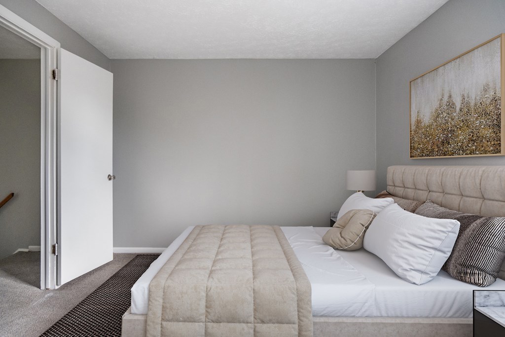 A bedroom with a large bed and a painting on the wall.