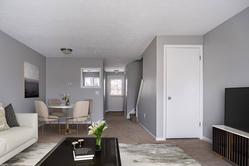 A living room with a white couch, a coffee table, and a television.