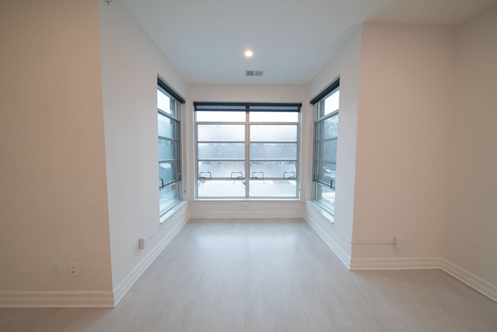 an empty living room with windows and wood floors