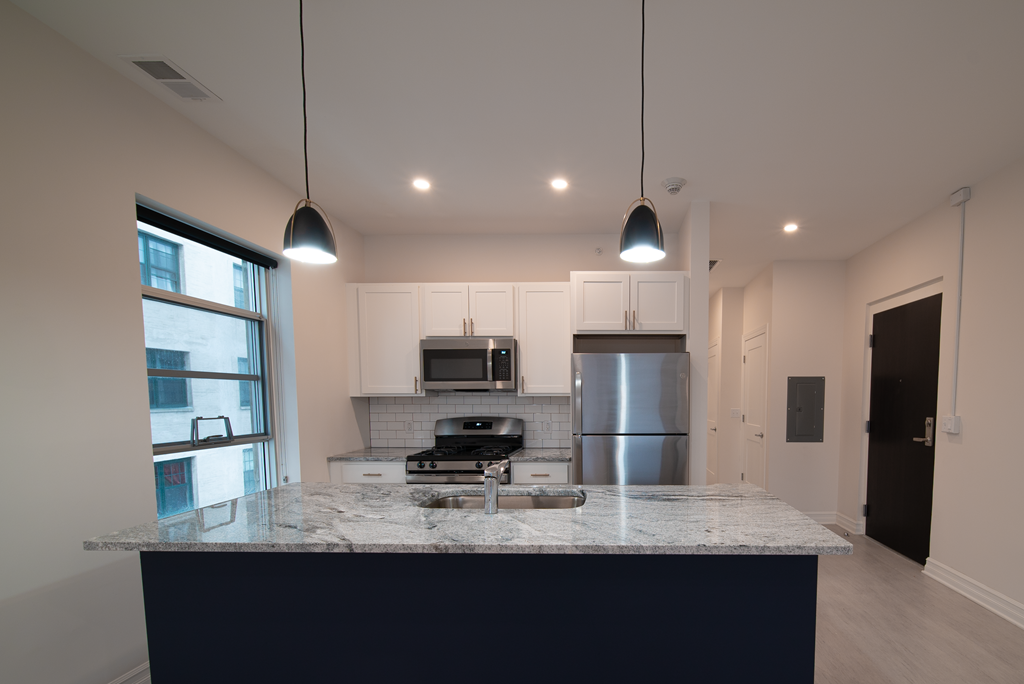 a kitchen with a marble counter top and a stainless steel refrigerator
