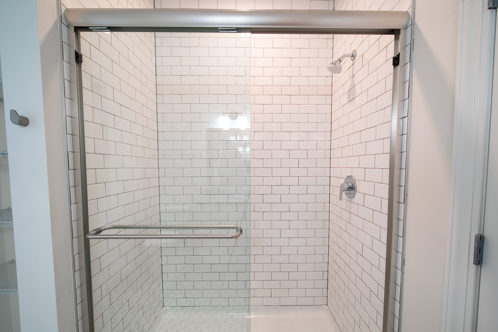 a white tiled shower with a glass door