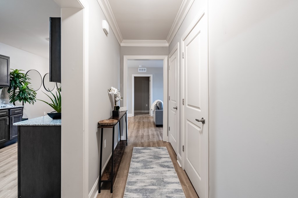 A long hallway with a rug on the floor and a door at the end.