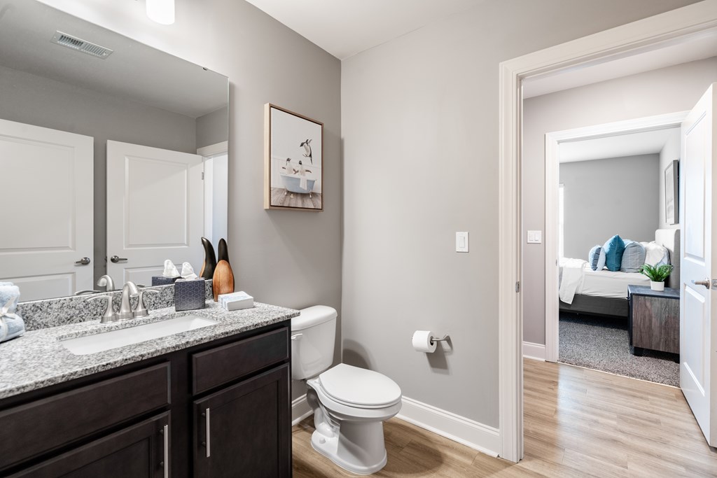 A bathroom with a toilet, sink, and mirror.