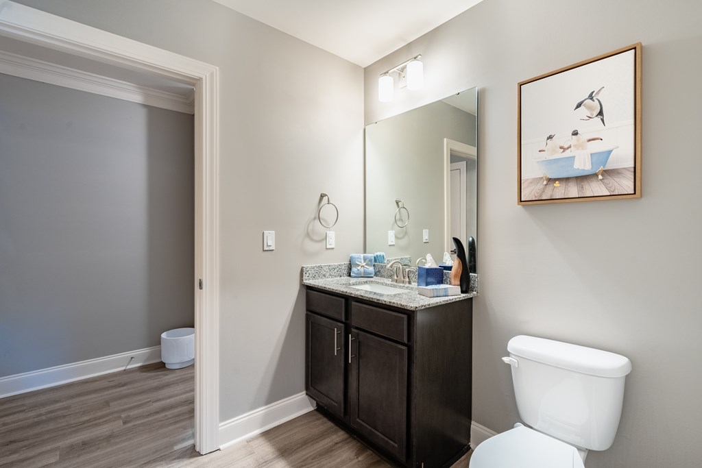 A bathroom with a toilet, sink, and a painting of a person swimming.