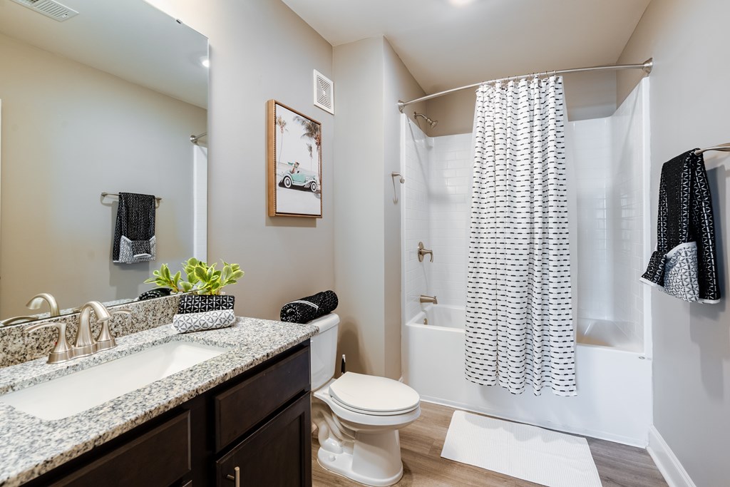 A bathroom with a white toilet, a sink with a mirror above it, and a shower with a curtain.