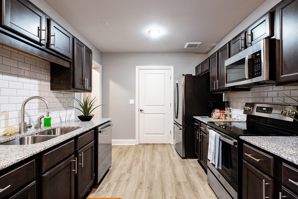 A kitchen with black cabinets and a white door.
