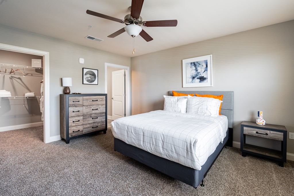 A bedroom with a bed, dresser, and nightstand.