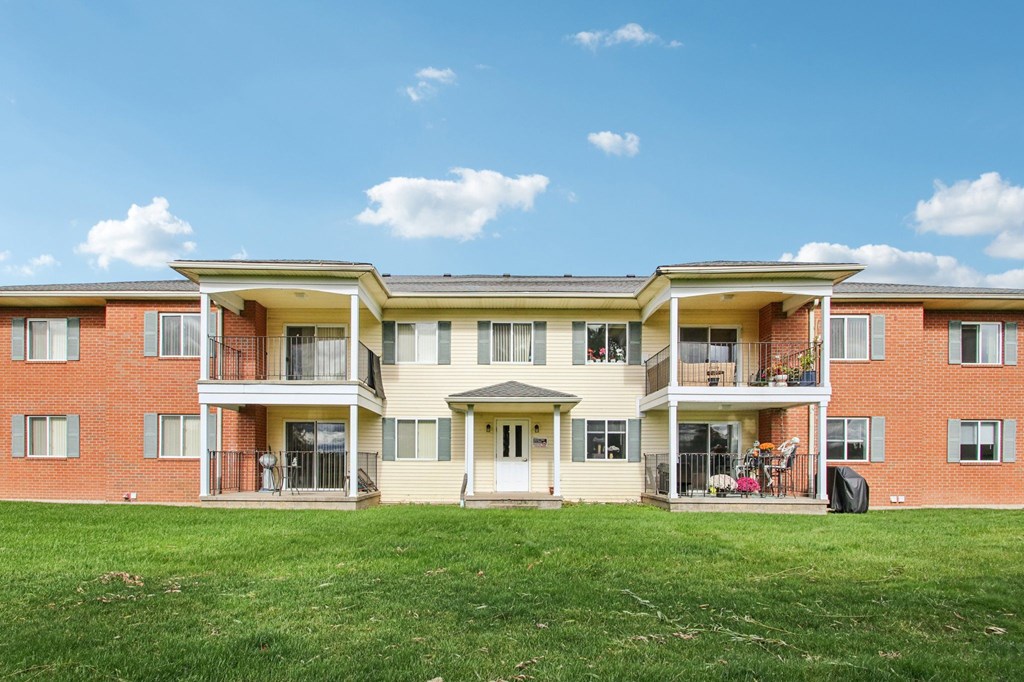 A large red brick apartment building with a green lawn in front.