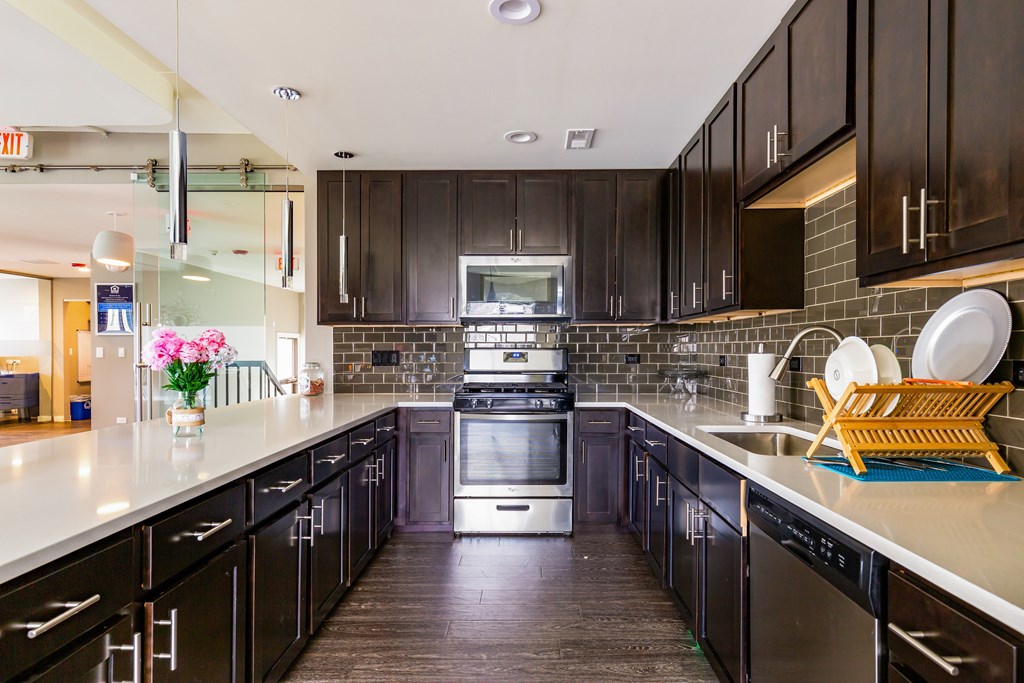 A kitchen with black cabinets and a stainless steel oven.