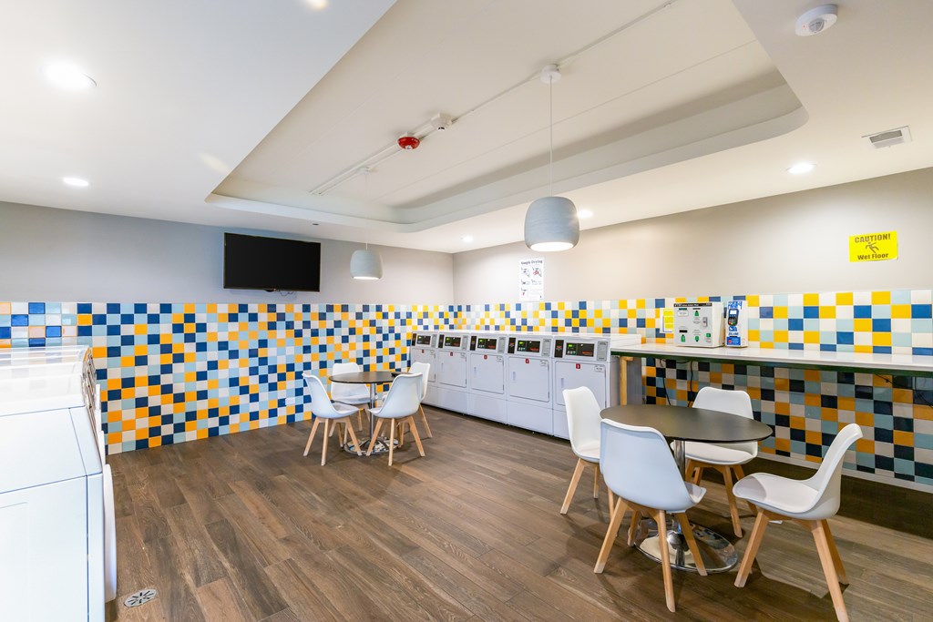 A kitchen with a white washing machine and a tiled wall.