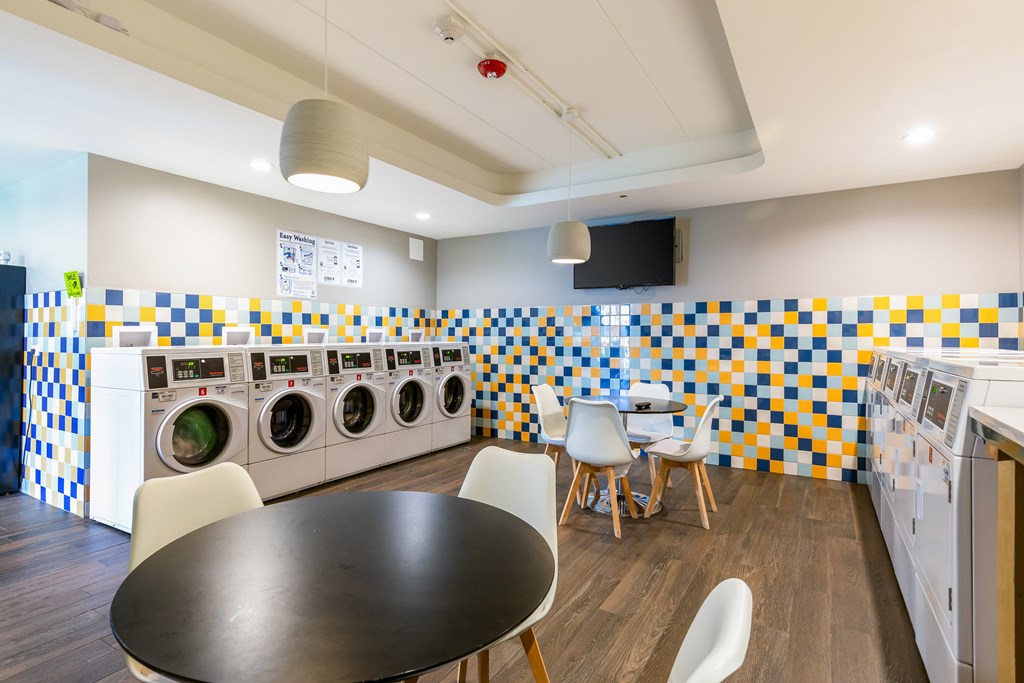 A laundry room with a washer and dryer on the wall and a table in the middle.