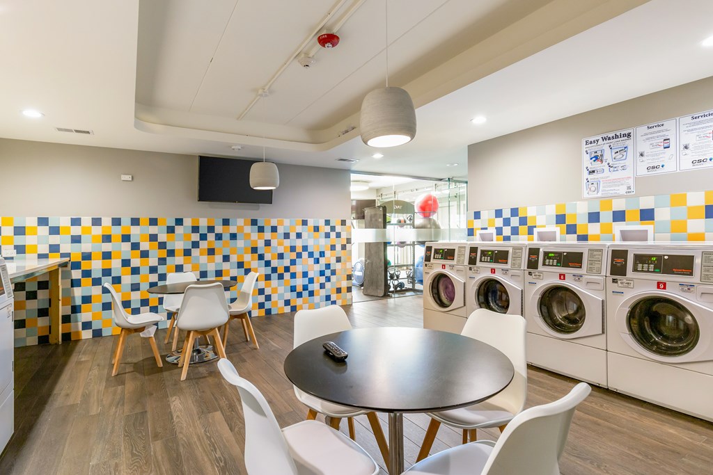 A laundromat with washers and dryers and a table and chairs.