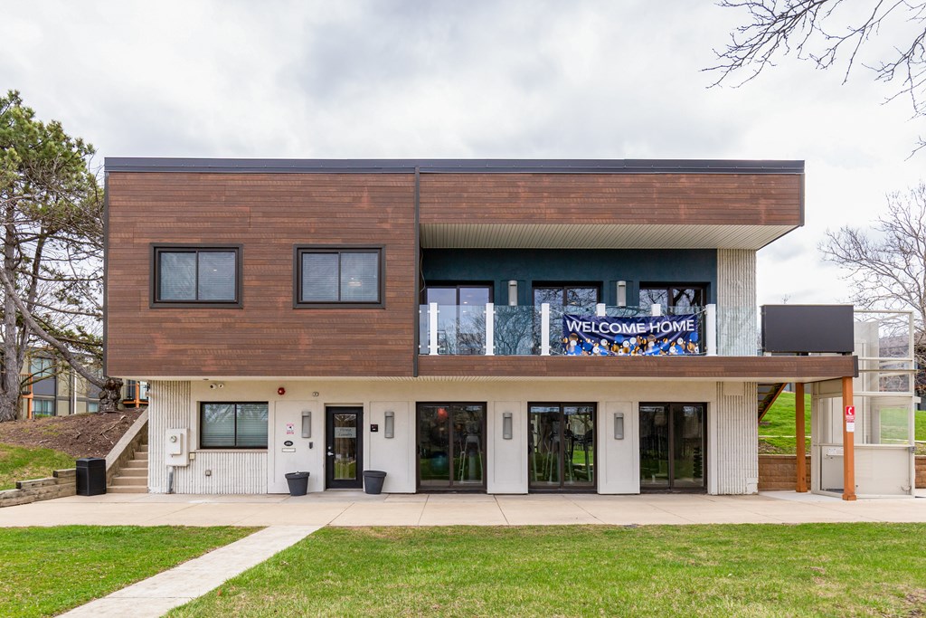 A modern building with a brown and white facade and a banner that says "Welcome Home".