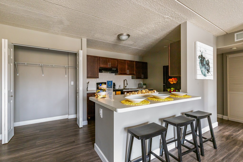 A kitchen with a bar stool and a fridge.
