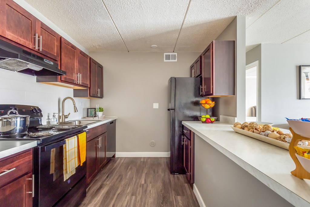 A kitchen with dark wood cabinets and a black refrigerator.
