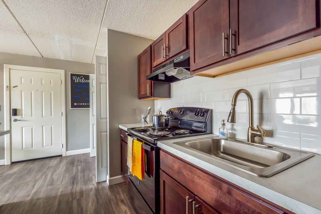 A kitchen with a sink, stove, and cabinets.
