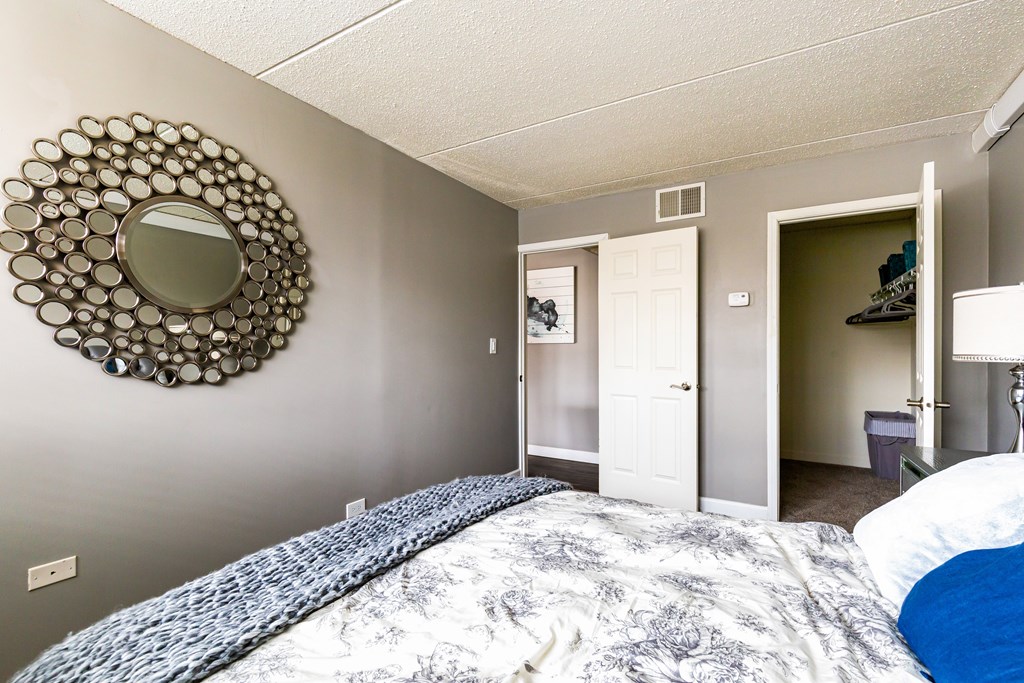 A bedroom with a bed and a mirror on the wall.