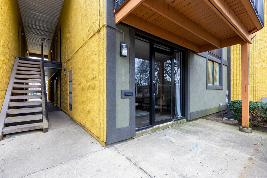 A yellow building with a wooden roof and a glass door.